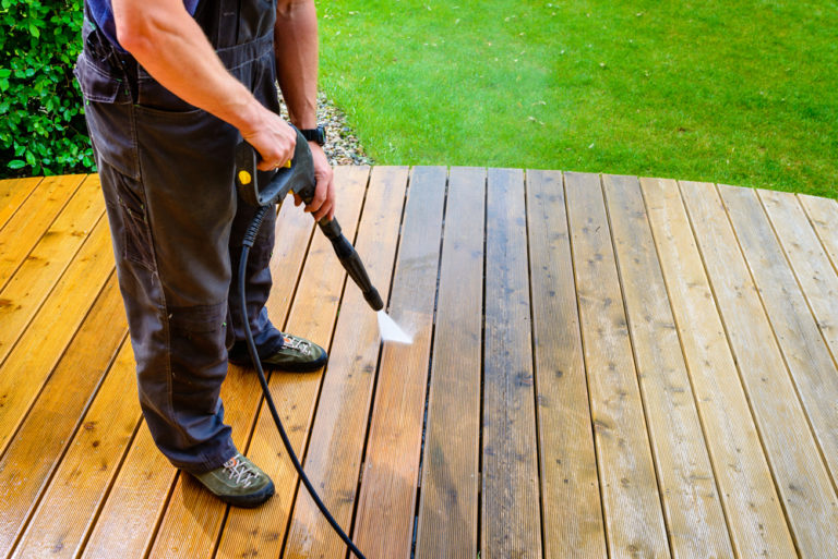 cleaning terrace with a power washer - high water pressure cleaner on wooden terrace surface