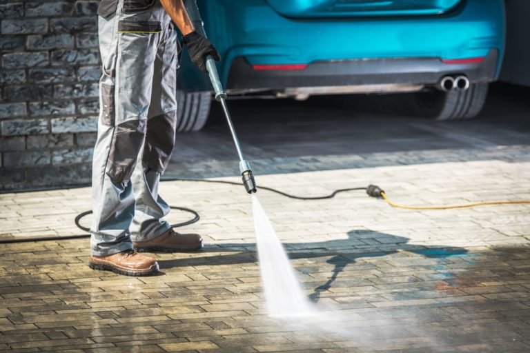 Cobble Driveway Pressure Washing by Caucasian Worker.