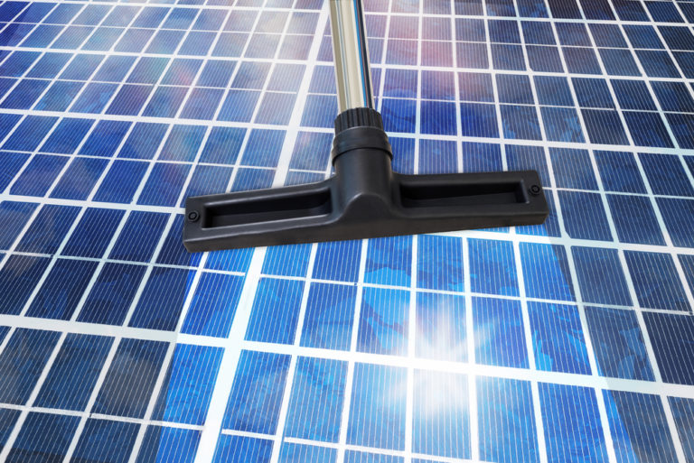 Close-Up Of A Cleansing Tool On Shiny Solar Panel Roof. Sustainable Energy Concept